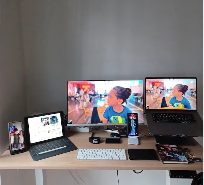 Ash’s desk: two monitors, a laptop and a tablet on a wooden desk.